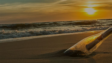 Message in a  bottle on beach at sunset
