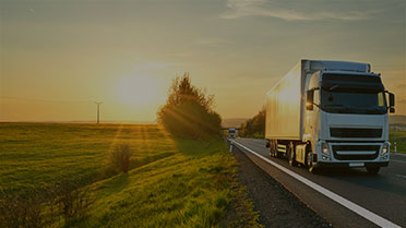 Truck traveling remote highway at sunset